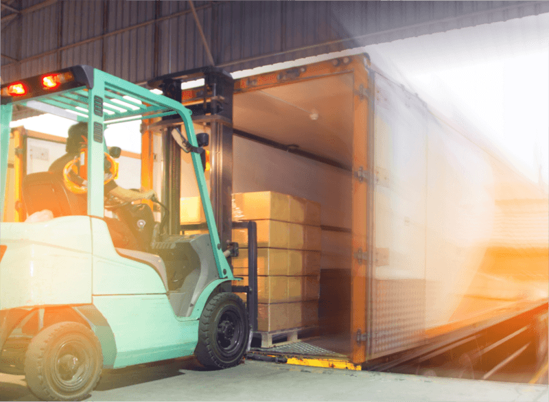 Forklift loading cargo onto a truck inside a warehouse